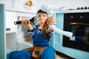 Young female plumber shows wrench and pipe