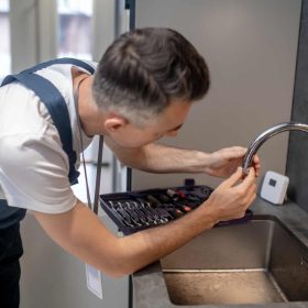 Man spinning faucet aerator on spout pipe